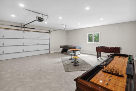 Spacious garage featuring a pool table, foosball table, and bright lighting.