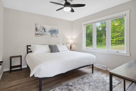 Modern bedroom interior featuring a large bed and natural light from a window.