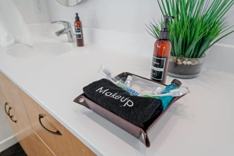 Bathroom countertop with a tray of personal care items, a towel, lotion bottle, and a small green plant.