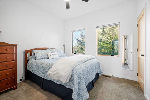Cozy bedroom featuring a wooden bed, blue bedding, and bright natural light.