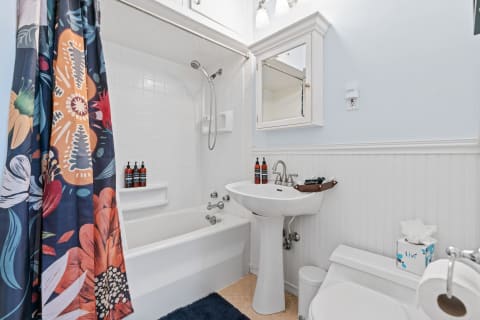 A styled bathroom showcasing a floral shower curtain, white bathtub, and a clean sink area.