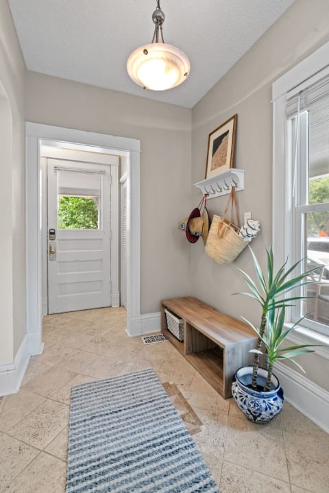 Stylish entryway with a wooden bench, a potted plant, and wall decor.