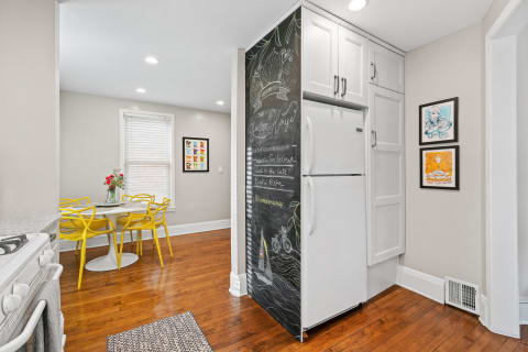A cozy kitchen with a chalkboard fridge, round table, and yellow chairs.