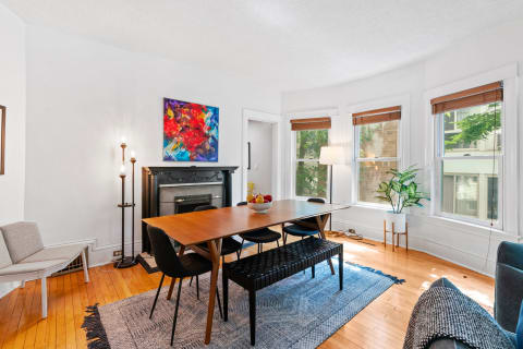 Modern dining room featuring a wooden table, colorful abstract art, and bright natural light.