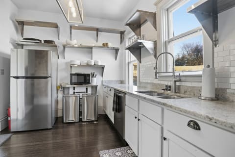 Modern kitchen with granite counters, stainless steel appliances, and open shelving.