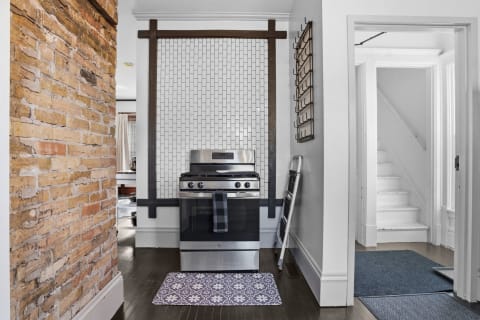 Stylish gas range in a modern kitchen with herringbone tile and exposed brick.