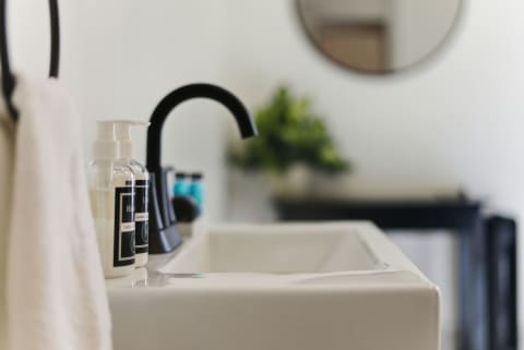 A stylish bathroom sink area showcasing soap and lotion dispensers, black faucet, and a white towel.