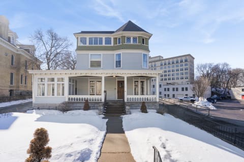 Victorian-style house surrounded by snow in downtown area with historic buildings nearby.