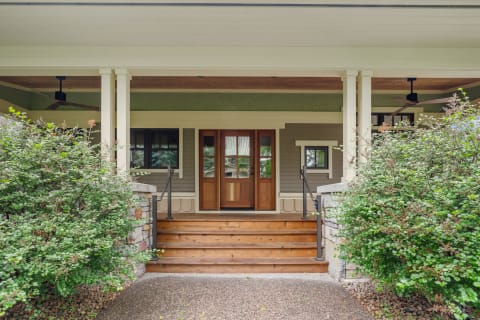 Entrance of a house with wooden doors and surrounding bushes.