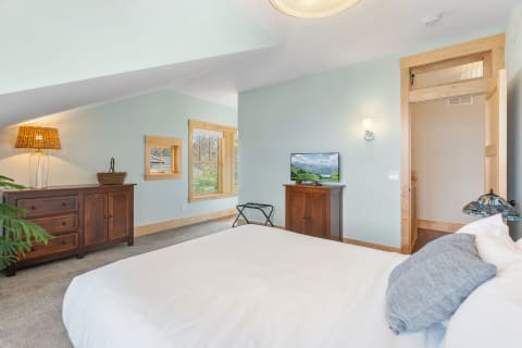 A cozy bedroom featuring a bed, wooden furniture, and natural light from windows.