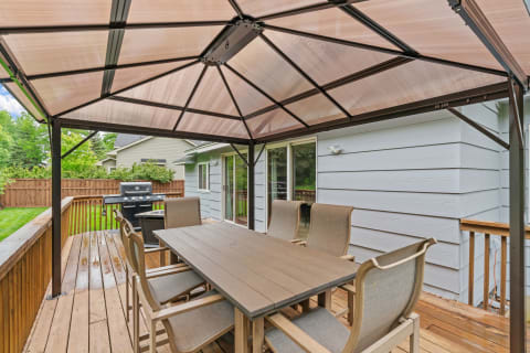 Outdoor dining space with a gazebo, table, and grill.