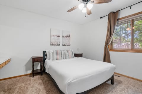 Cozy bedroom with a large bed, nightstands, and natural light from a window.