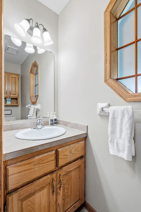 Interior view of a neat bathroom with light gray walls, wooden cabinets, and modern fixtures.