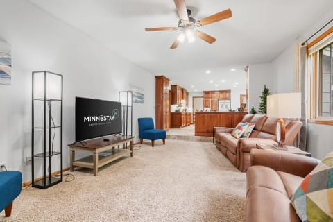 Comfortable living room featuring leather couch, colorful accents, and a view of the kitchen.