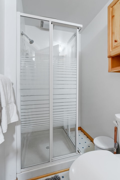 A clean and modern bathroom with a glass shower stall and white towels.