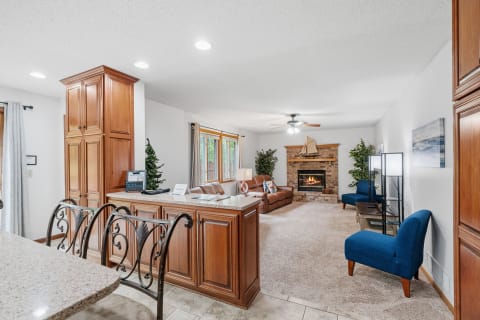 Bright and inviting living room featuring brown sofa, stone fireplace, and blue chairs.