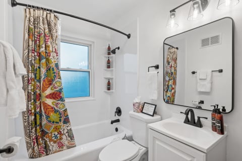 A bright bathroom with a vibrant shower curtain and contemporary vanity.