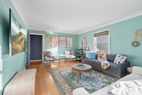 A vibrant living room with teal walls, modern furniture, and artistic decor.