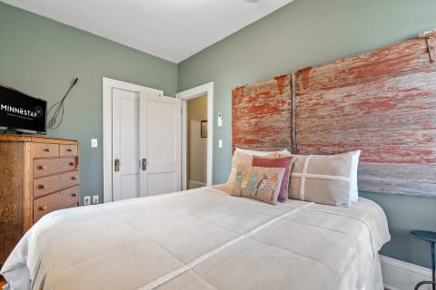 A cozy bedroom with a vintage wooden dresser and a rustic red headboard.
