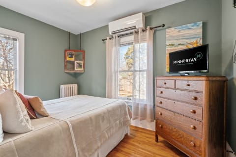 Interior view of a green-themed bedroom with a bed, wooden dresser, and TV.