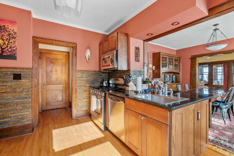 Comfortable kitchen featuring coral walls, a stone-tiled backsplash, and stainless steel appliances.