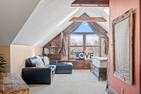 A stylish attic lounge with a leather sofa, wooden beams, and cozy decor.