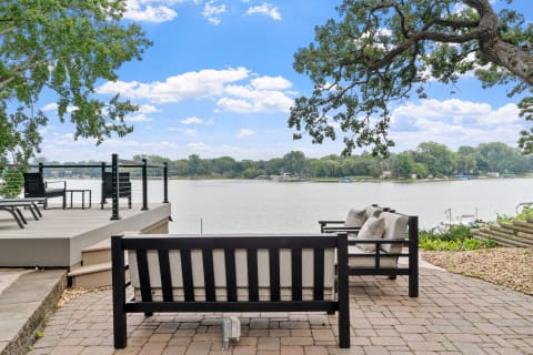 Lakeside patio with modern seating and views of trees and water.