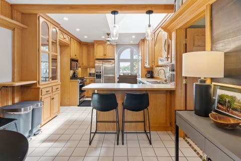 Kitchen with oak cabinets, stainless steel appliances, and a black island with bar stools.