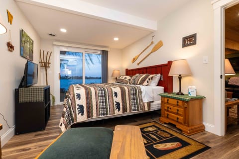 Interior of a cozy bedroom featuring a bed, TV, and a lakeside view.
