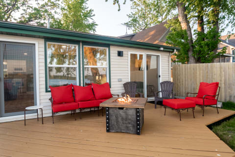 Outdoor seating area with red cushions and a fire pit on a wooden deck.