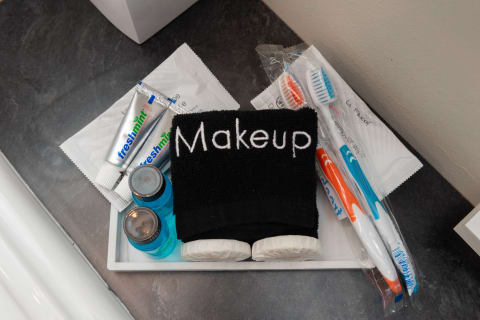 A tray containing personal care items such as a black makeup cloth, blue liquid bottles, freshmint toothpaste, and toothbrushes.