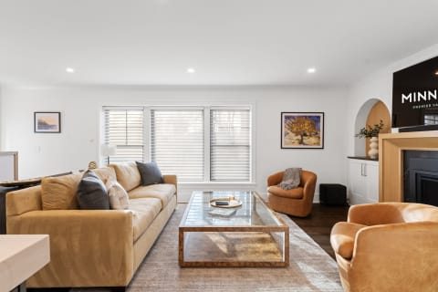 Stylish modern living room with beige couch, glass coffee table, and warm armchairs.