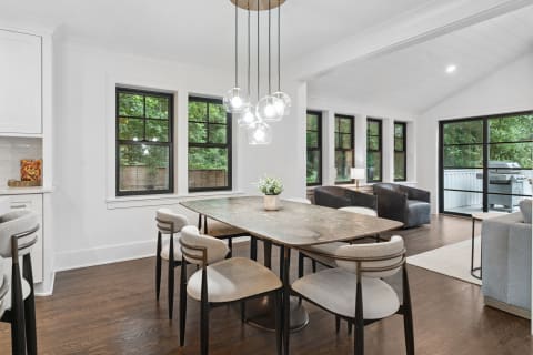 A contemporary dining area featuring a stylish table and modern chairs, with large windows letting in natural light.