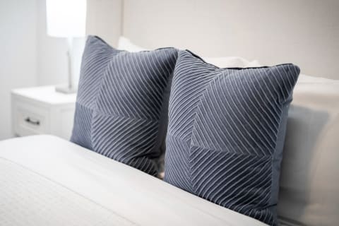 Close-up of navy blue decorative pillows with a patterned texture on a bed.