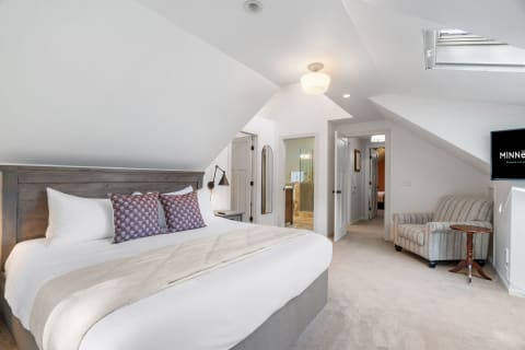 A cozy bedroom featuring a large bed, decorative pillows, and a skylight.