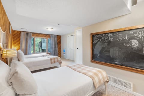 Cozy children's bedroom featuring three beds, a chalkboard, and wooden accents.