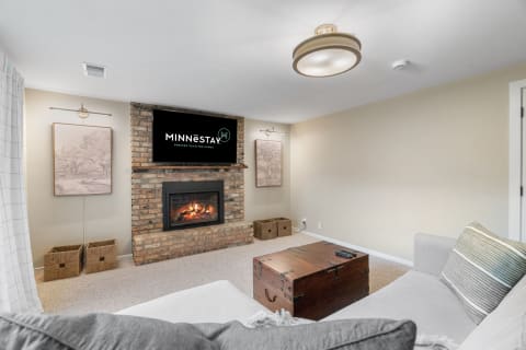 A warm living room with a brick fireplace, mounted television, and cozy furnishings.
