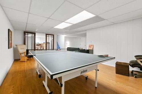 Your game room awaits with a professional ping pong table, comfy seating, and natural light streaming through skylights.