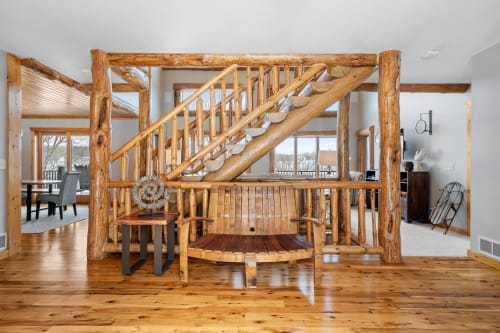 Step into rustic elegance with this stunning log staircase featuring handcrafted wooden railings and rich hardwood floors throughout your mountain retreat.