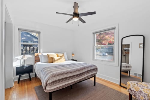 Rest peacefully in your bright bedroom with modern touches, plush bedding, and charming street views framed by tall windows.