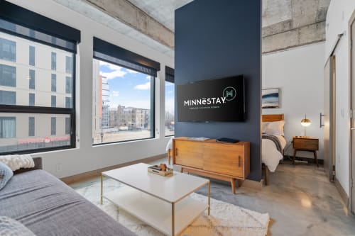 Relax in your modern loft-style living room where mid-century furnishings meet exposed beams and city views through floor-to-ceiling windows.