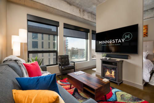 Unwind in your stylish loft living room with exposed concrete beams, cozy fireplace, and vibrant accents overlooking the city.