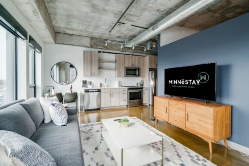 Unwind in your modern loft with exposed concrete ceilings, sleek kitchen, and cozy seating area perfect for relaxing after exploring the city.