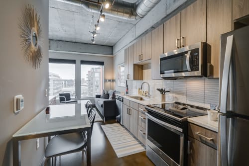 Your sleek modern kitchen features warm wood cabinetry, stainless steel appliances, and a cozy breakfast nook where you can enjoy morning coffee with city views.