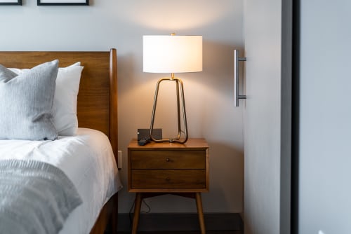 Sink into crisp white linens and enjoy the warm glow of your stylish bedside lamp in this thoughtfully designed bedroom retreat.