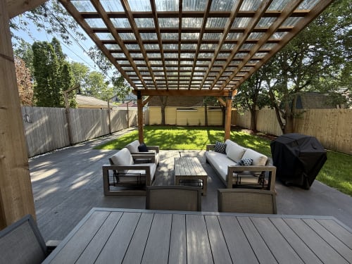 Relax in your private outdoor oasis with comfortable seating under the elegant pergola, overlooking lush green lawn.