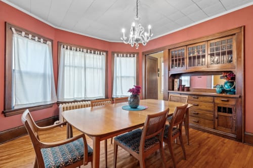 Gather around your elegant dining table beneath the crystal chandelier, where warm coral walls and rich wood create perfect moments for memorable meals.